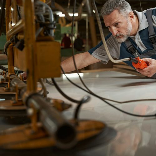 Close up of bearded man checking the woodworking machine